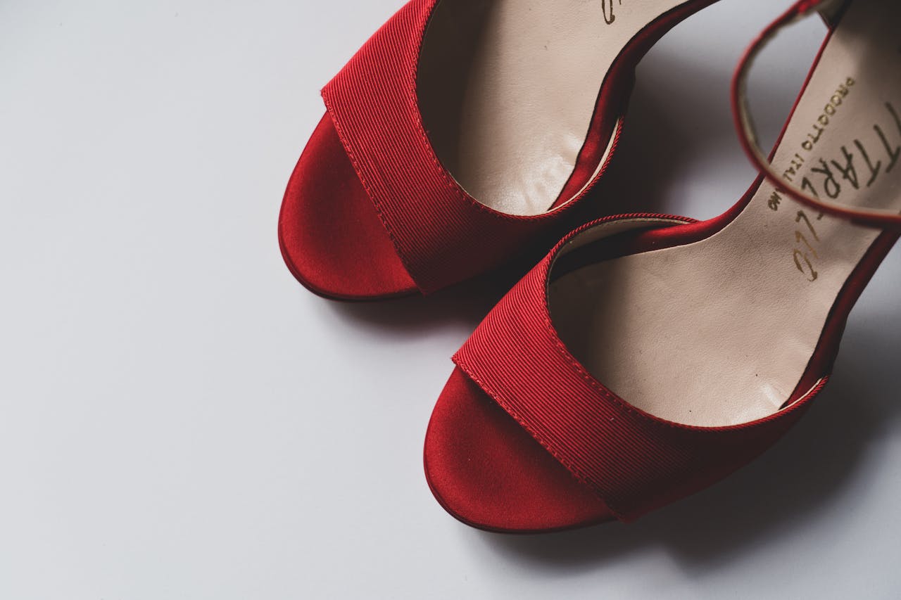 Stylish red high-heeled shoes on a white surface, perfect for fashion and romantic themes.